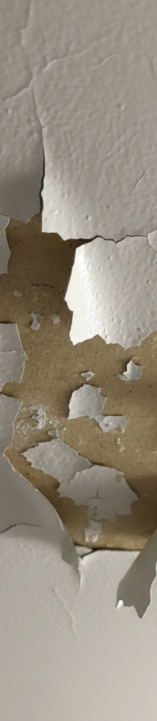 Close-up of a white bathroom ceiling with paint peeling and cracking due to moisture damage.