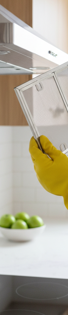A person holding a sparkling clean metal range hood filter, ready to be reinstalled into the hood above a stove.