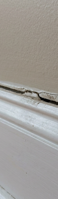 Baseboard trim pulling away from drywall leaving a dark visible gap along the wall