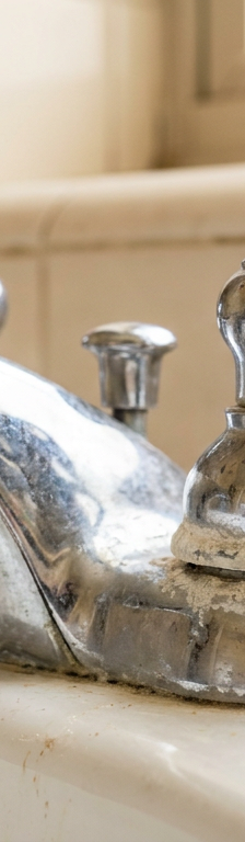 Corroded bathroom faucet handle stuck on sink vanity with white mineral buildup