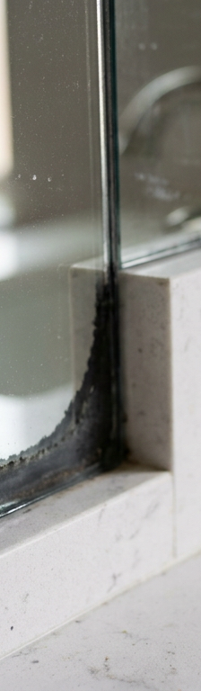 Black creeping desilvering edges along the bottom corner of a bathroom plate glass vanity mirror