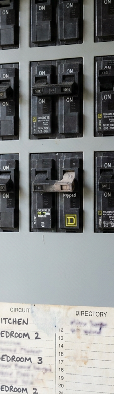 A tripped circuit breaker in a home electrical panel, with the switch out of alignment from the other breakers.
