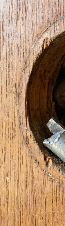 A disassembled door lock showing a sheared metal tailpiece and open deadbolt mechanism on a door frame