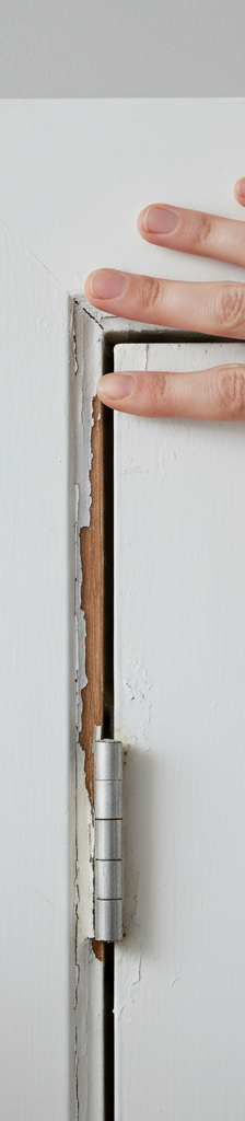 Close-up of a white painted door trim with a vertical split, illustrating common door trim damage.