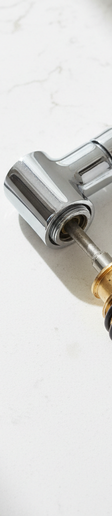 Disassembled single-handle kitchen faucet with cartridge, O-rings, and tools laid out on a countertop.