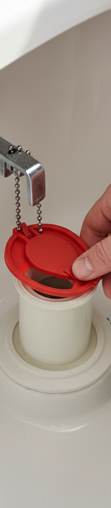 Hand replacing a red flapper valve in a toilet tank to fix a running toilet.