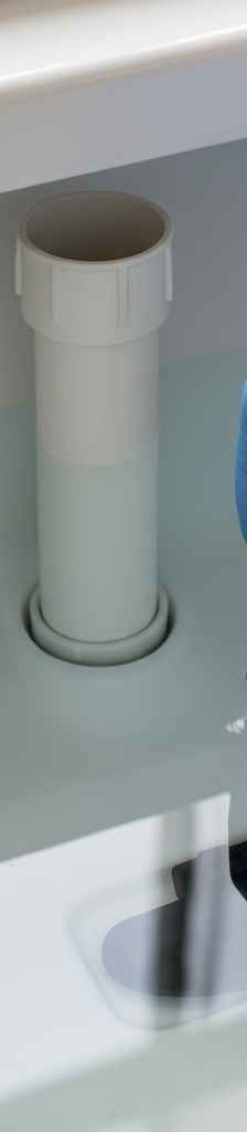 Hand adjusting a toilet flapper chain inside a clean toilet tank