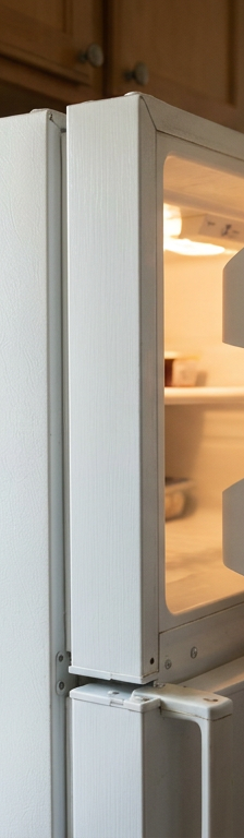 A white refrigerator door slightly ajar, showing that it failed to seal and stay shut.