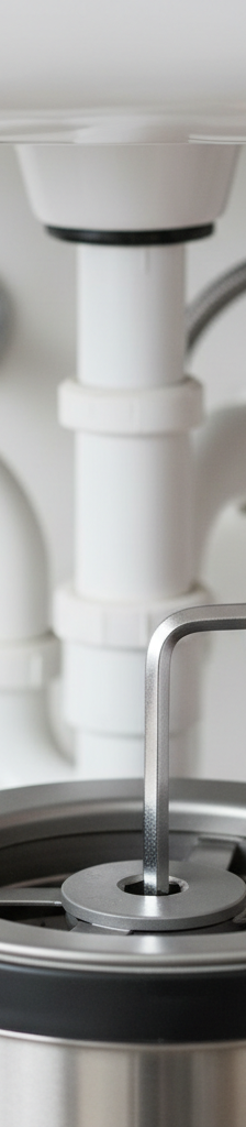 Hand inserting an Allen wrench into the bottom of a garbage disposal to clear a jam.
