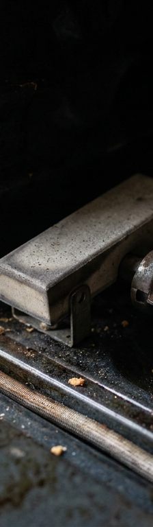 A close-up of a failed gas oven igniter inside an unlit oven, showing the part that needs to be replaced.