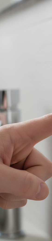 Homeowner's hand pressing the reset button on a white GFCI electrical outlet in a kitchen.