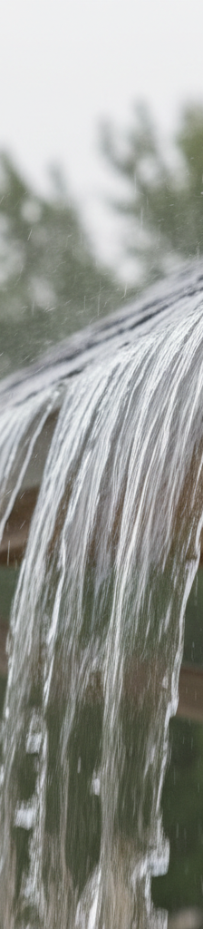 Overflowing gutter during heavy rain, showing water cascading over the edge.