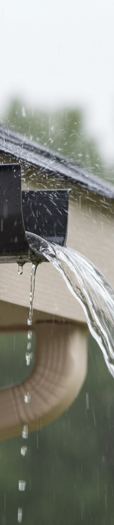 Clean gutter with proper pitch, showing water flowing smoothly towards downspout during heavy rain