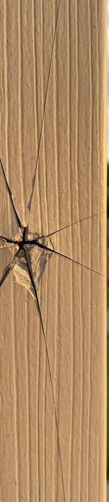 Close-up of residential vinyl siding showing characteristic star-shaped crack from hail impact