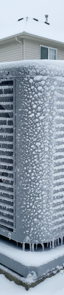 Heat pump outdoor unit covered in frost and ice during cold weather.