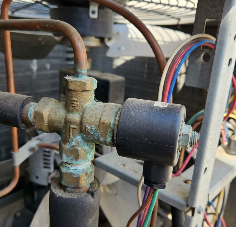 A close-up of a heat pump reversing valve, the part that switches the unit from heat to AC.