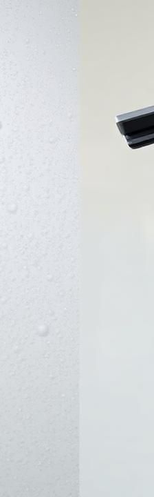 Glass shower door with cloudy hard water stains being squeegeed clean