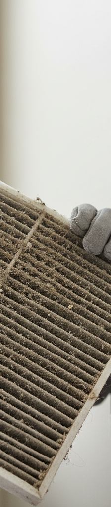 Homeowner inspecting a severely clogged HVAC air filter, highlighting a common cause of short cycling.