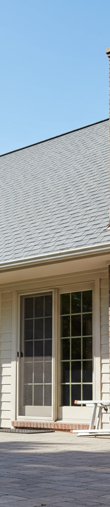 Homeowner inspecting roof flashing around a chimney with binoculars from the ground.