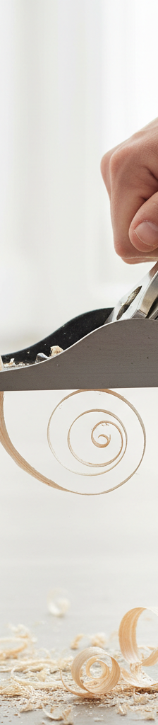 Homeowner uses a block plane to shave wood off a sticking interior door edge.