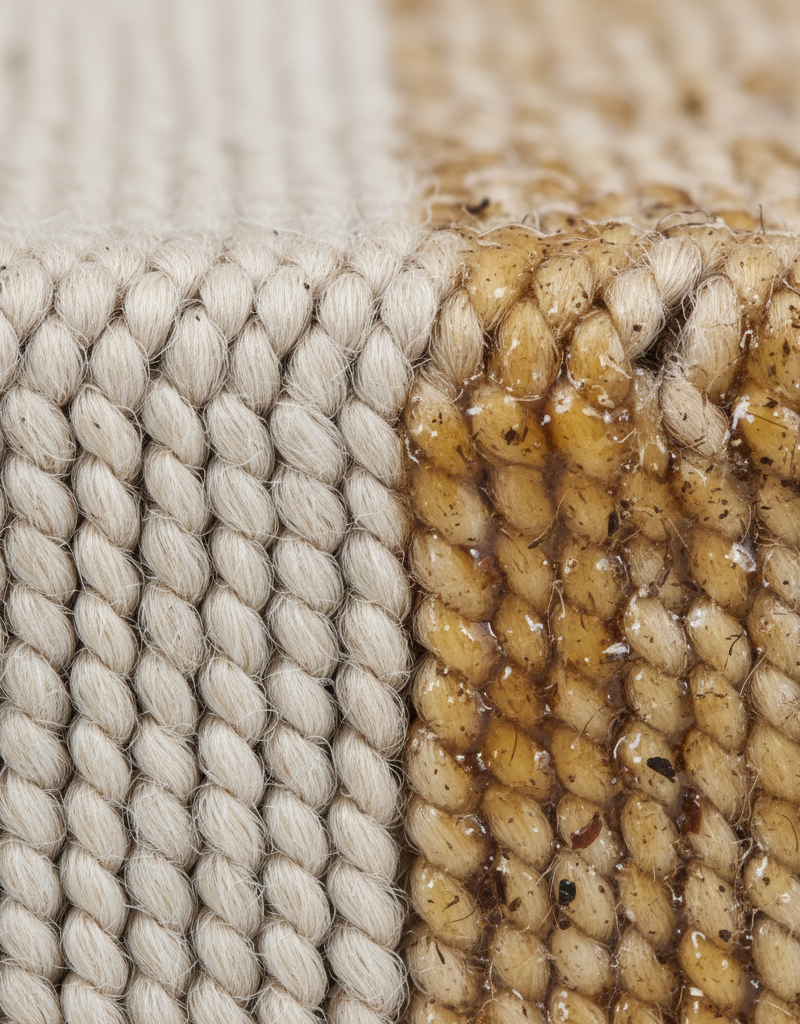 Close-up of carpet fibers, some clean and fluffy, others matted with a translucent, sticky residue trapping dirt particles.
