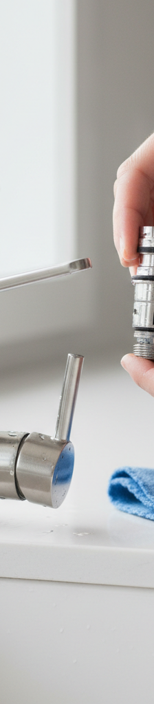 Homeowner repairing a leaky single-handle kitchen faucet by replacing the cartridge