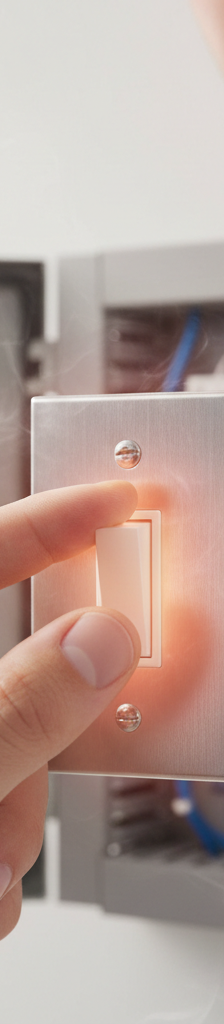 A homeowner's hand carefully touching a light switch that appears hot, with a concerned expression.