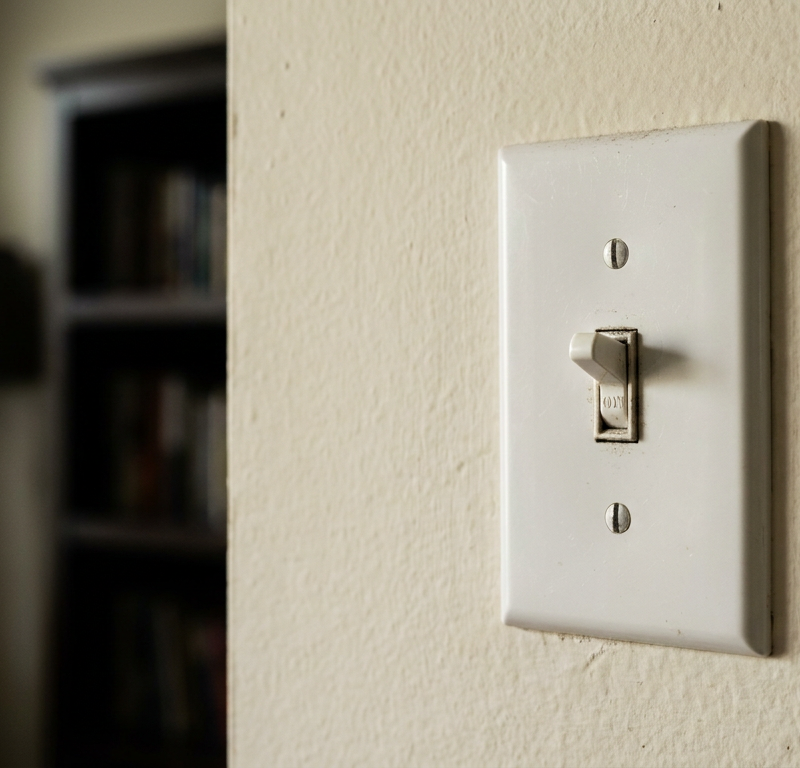 A non-working white light switch on a wall, stuck in the on position but the light is not on.
