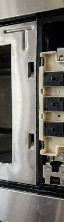 Close up of a microwave's faulty door interlock switches, which can cause it to stop running after a few seconds.