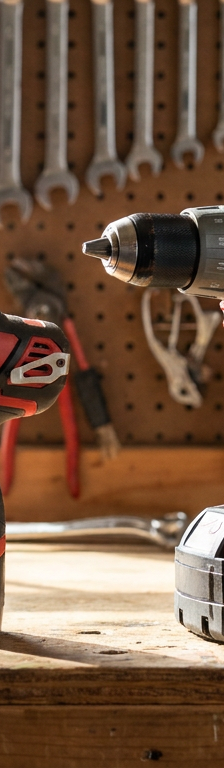 A Milwaukee M12 drill and a Milwaukee M18 drill shown side-by-side on a workbench.