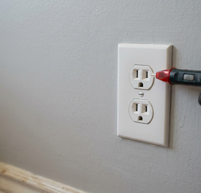 A dead electrical outlet being tested with a non-contact voltage tester.