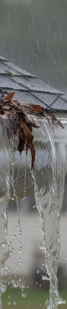 Water overflowing from a clogged house gutter during a heavy rainstorm