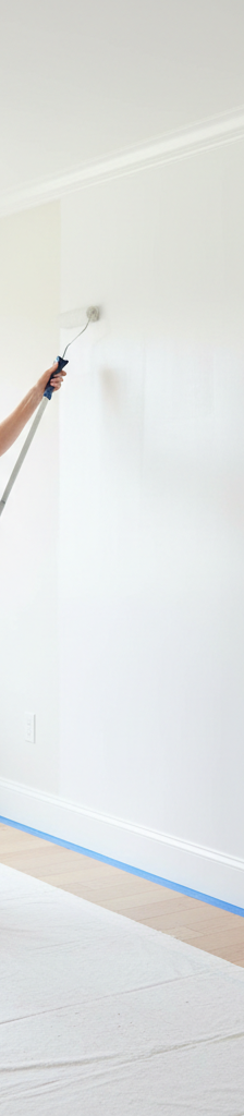 A homeowner skillfully painting an interior wall with a roller, ensuring a smooth and even finish.
