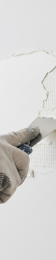 Hand applying joint compound to a self-adhesive drywall patch on a white wall.