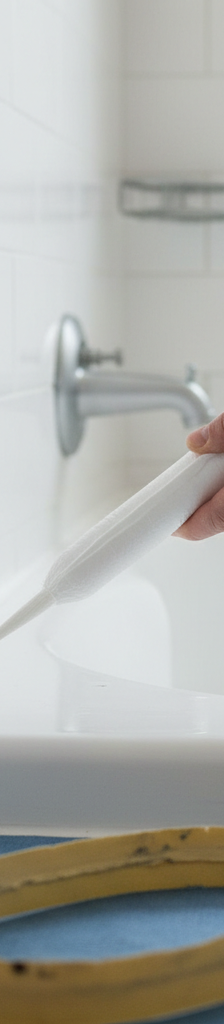 Close-up of a perfectly applied bead of fresh white silicone caulk on a bathtub edge.