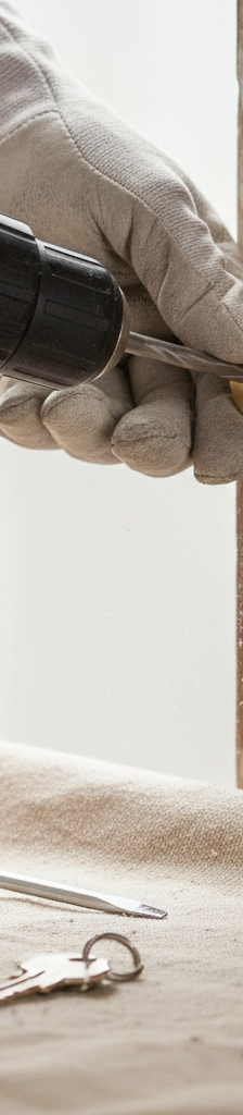 Hands installing a new silver deadbolt lock on a brown wooden door with a screwdriver.