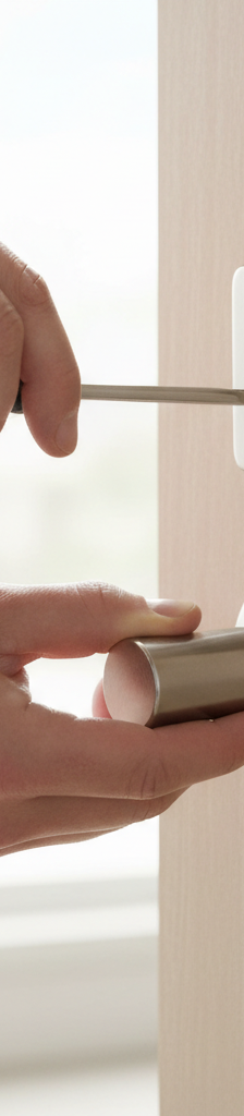 Homeowner's hands tightening screws on a new silver deadbolt lock installation