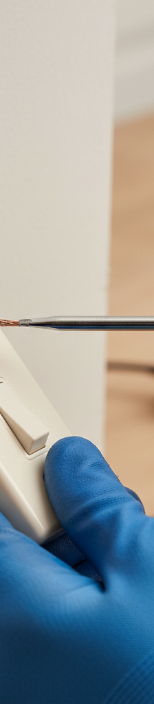 Homeowner carefully disconnecting a black wire from a light switch with a screwdriver