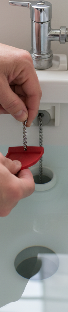 Homeowner inspecting the flapper valve and chain inside a toilet tank to fix a running toilet.