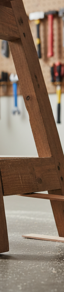Contractor shimming a wobbly sawhorse leg in a workshop