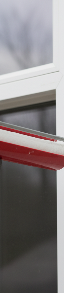 Homeowner applying caulk to seal a drafty window frame, demonstrating DIY air leak repair