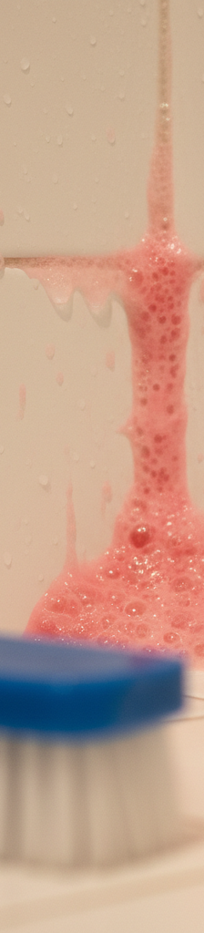 Close-up of pink slime, the bacteria Serratia marcescens, growing on white shower grout lines.