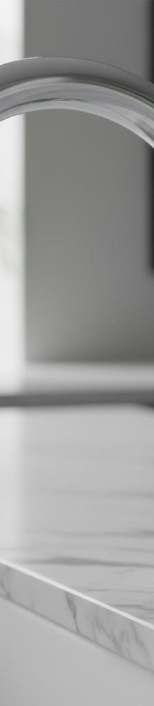 Close-up of a chrome single-handle kitchen faucet with a single droplet of water hanging from the spout