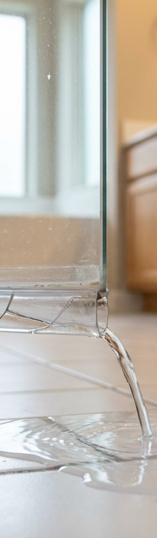 A shower door leaking water from the bottom seal onto a tile bathroom floor.
