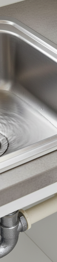 Kitchen sink with slow draining water, showing the P-trap underneath, indicating a common plumbing issue.