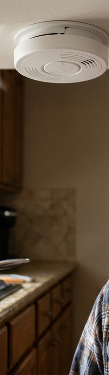 A smoke detector on a ceiling blaring during cooking, causing a frustrating false alarm in the kitchen.
