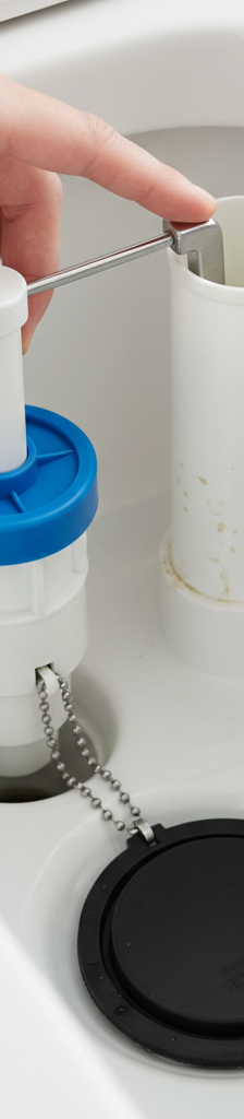 Inside a toilet tank showing the water level, fill valve, and flapper, being adjusted by a homeowner's hand