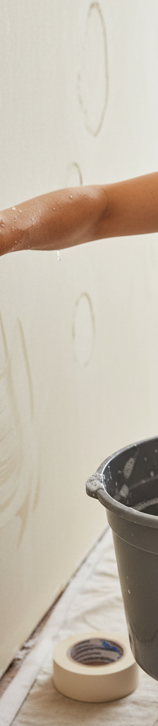 Homeowner meticulously cleaning a wall with a sponge and bucket before painting