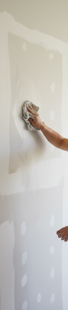 Homeowner cleaning a wall before painting, showing patched areas