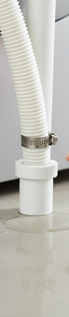 Homeowner inspecting a leaking washing machine drain hose connected to a standpipe.